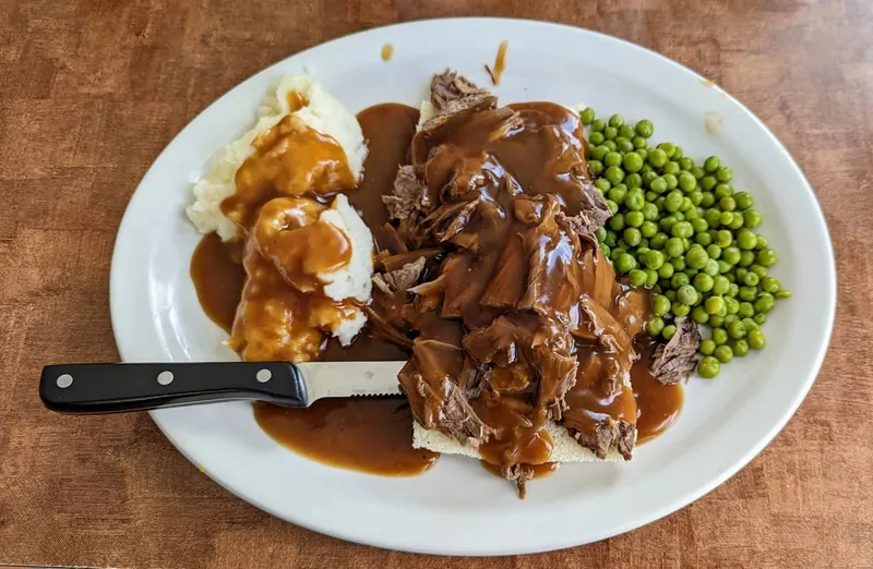 Open-faced hot plate with gravy, mashed potatoes and peas