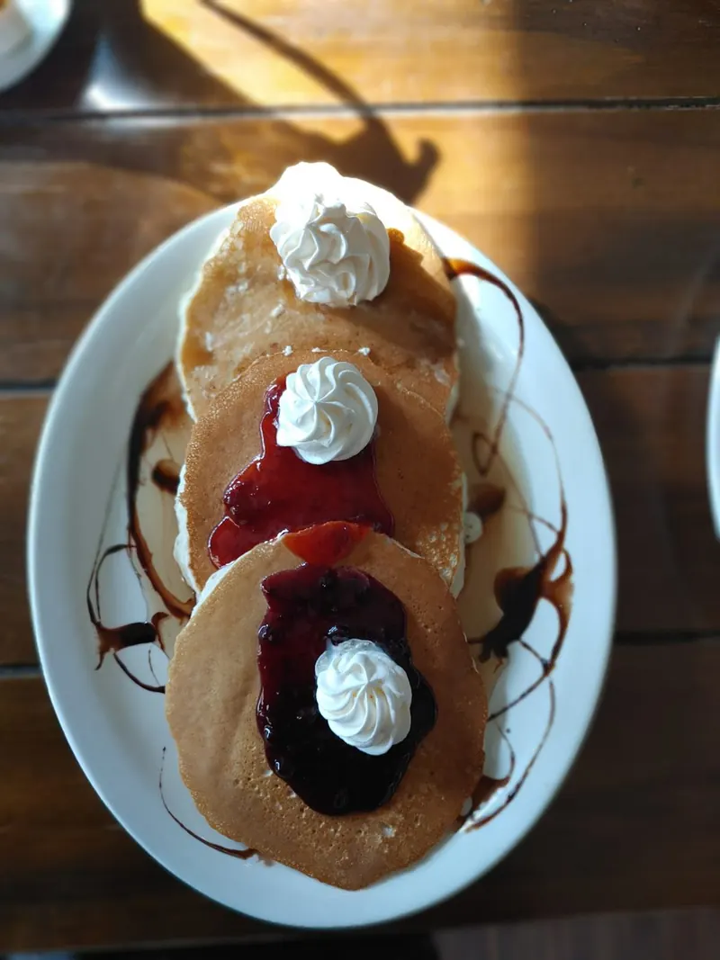 Stack of pancakes with berry topping and whipped cream